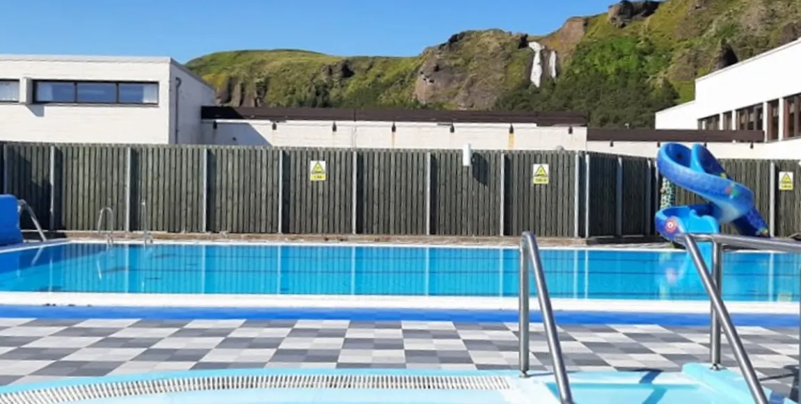 Sundlaugin Kirkjubæjarklaustri og Systrafoss í bakgrunninn